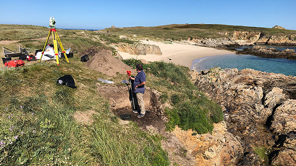 Researcher with instruments on excavation site on the coast